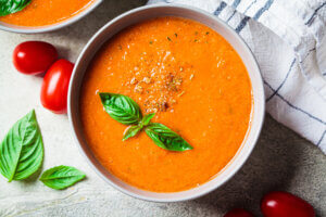 traditional gaspacho in gray bowl. summer tomato soup with basil